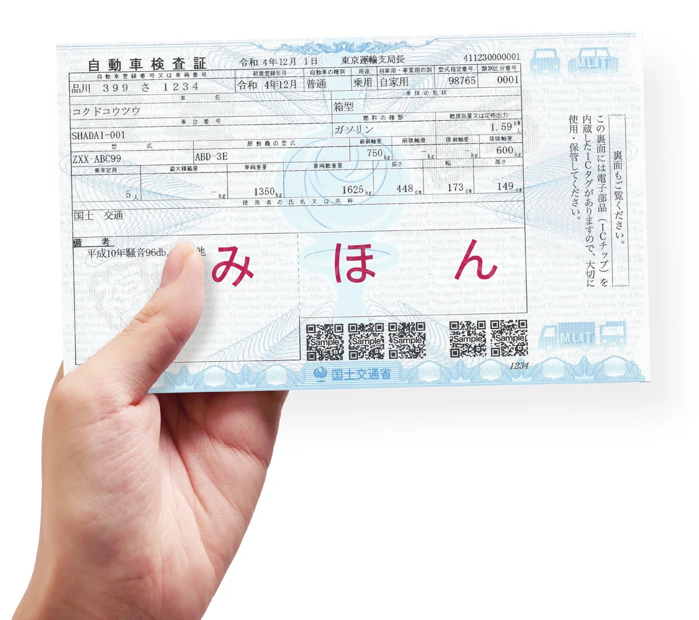 電子車検証の見本を手に持った写真。A6相当の厚紙で、券面下部に二次元コードがある